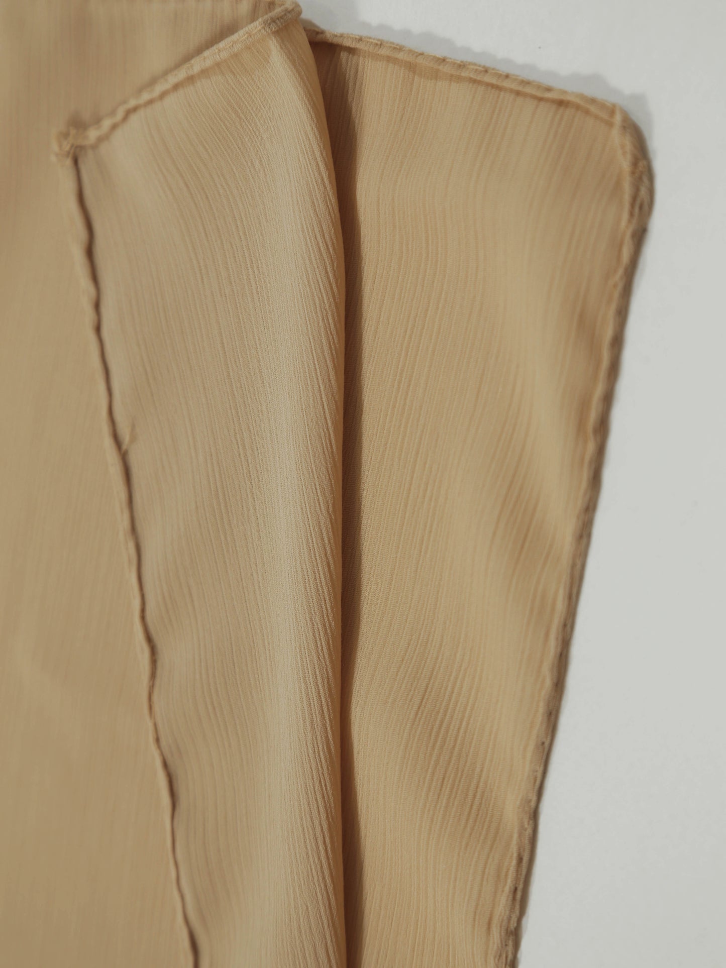Close-up of textured fabric edges in soft brown tones of Crinkle Georgette - Mocha material.