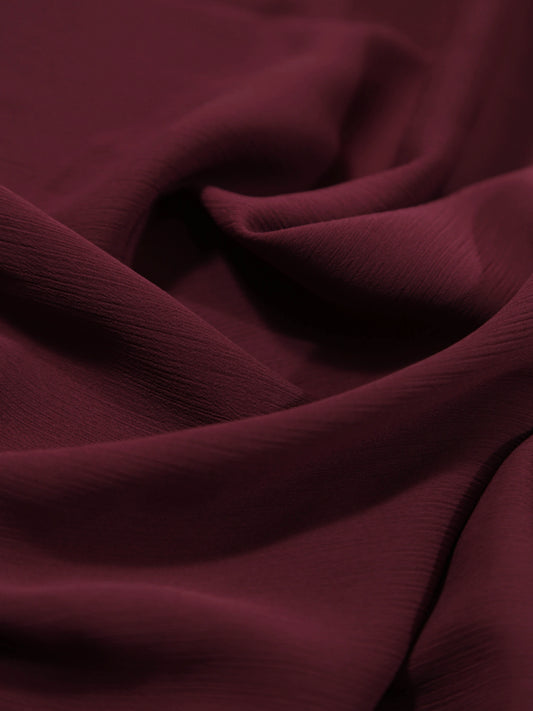 Close-up of soft textured Crinkle Georgette - Maroon fabric with gentle folds and rich color tone.