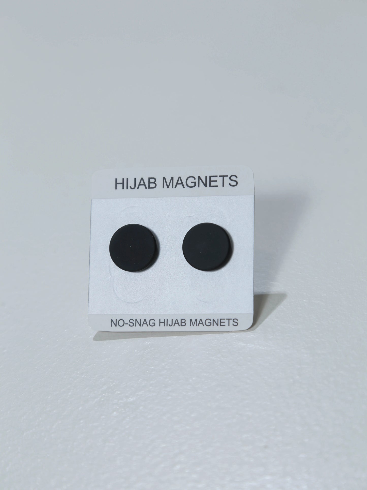 Black hijab magnets on a white card with text on a white background