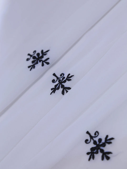 White fabric with black floral embroidery on a white background