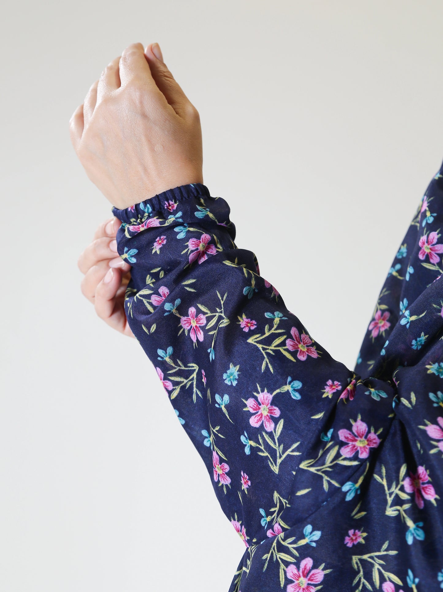 Navy blue long-sleeve top with floral pattern worn by a person, on a plain background.