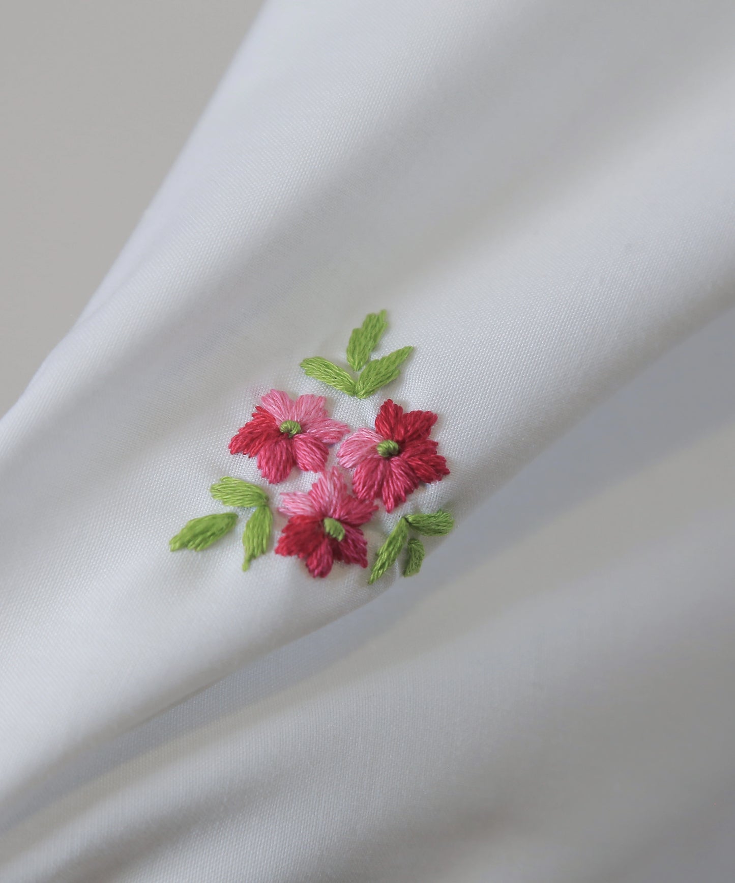 Embroidered red flowers with green leaves on a white embroidered namaz chadar