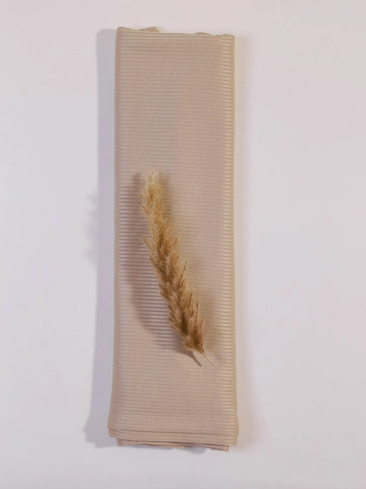 Beige ribbed fabric with a dried plant on a white background