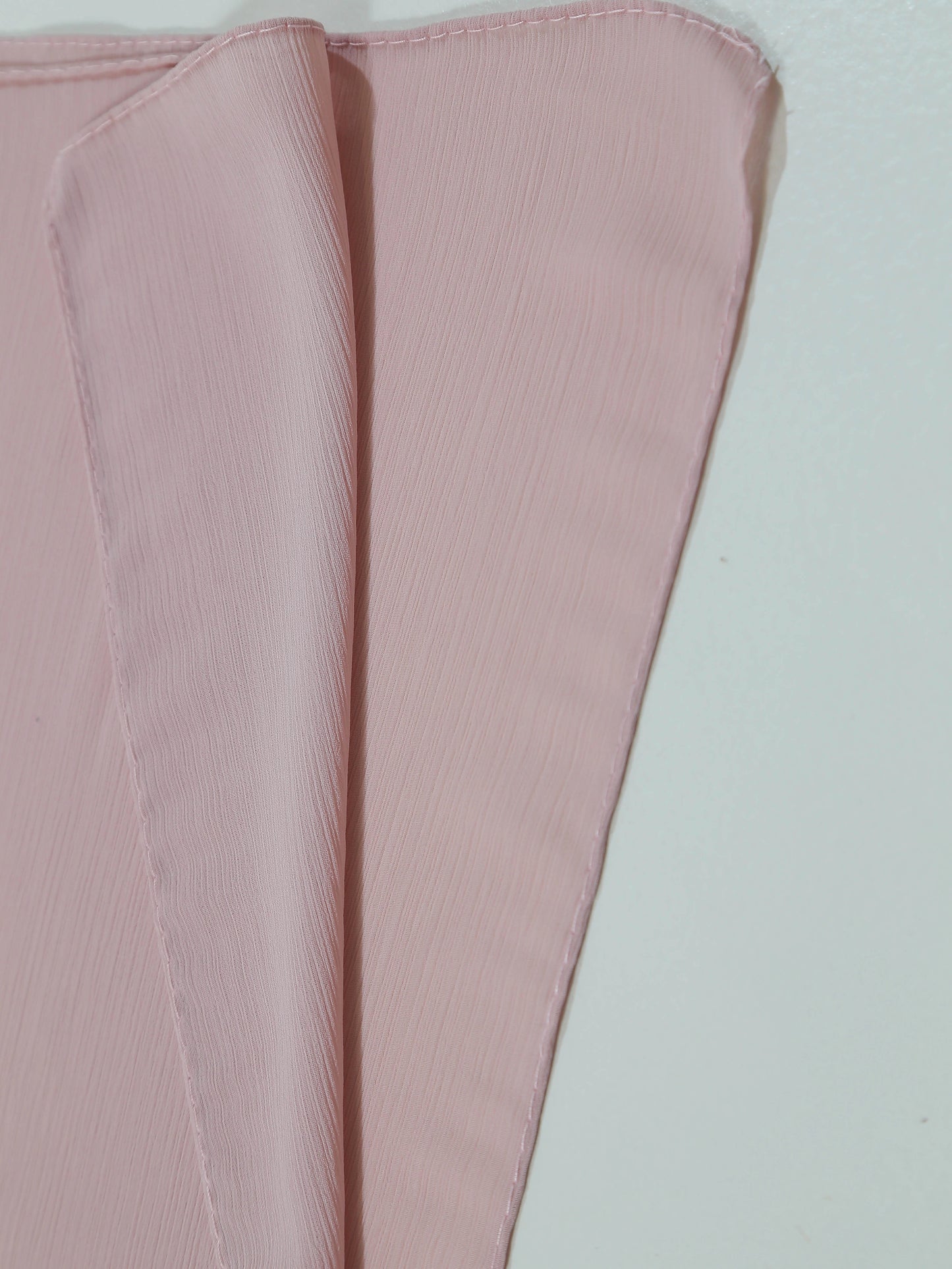 Soft textured fabric swatch in pale pink showing folds and fine crinkle details, Crinkle Georgette - Powder Pink.