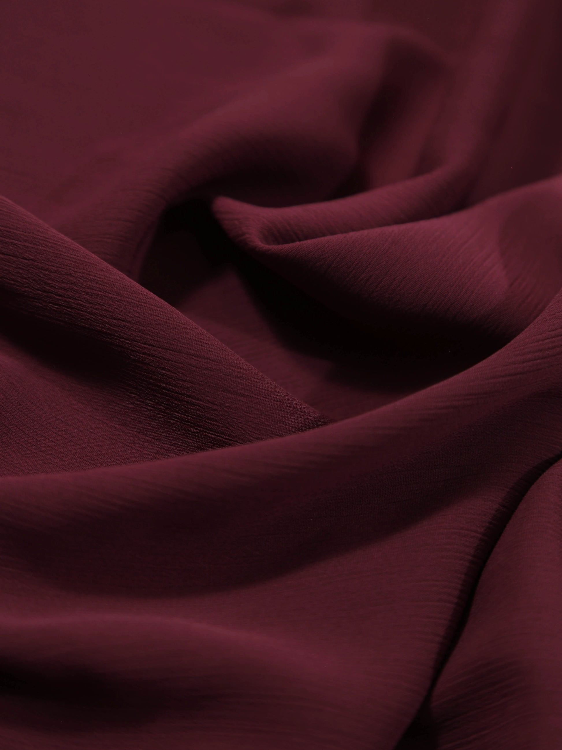 Close-up of soft textured Crinkle Georgette - Maroon fabric with gentle folds and rich color tone.