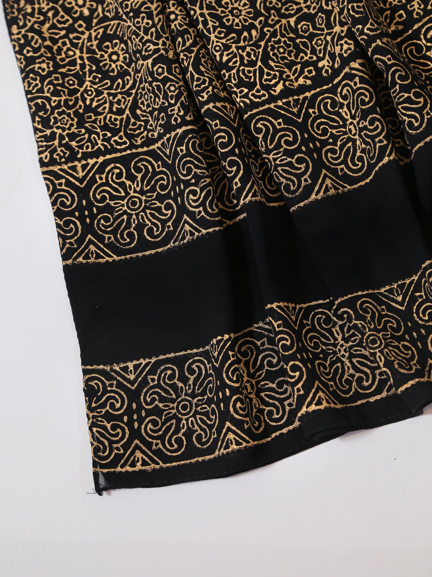 Black fabric with gold intricate patterns on a white background