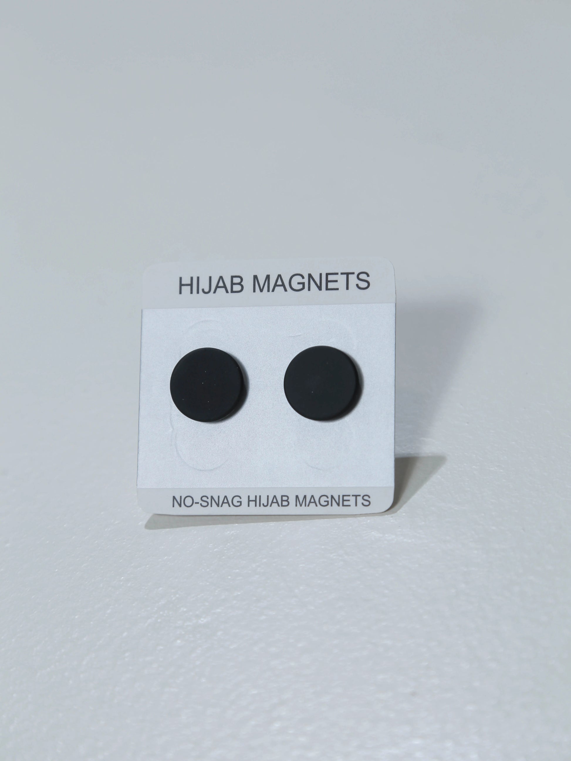 Black hijab magnets on a white card with text on a white background