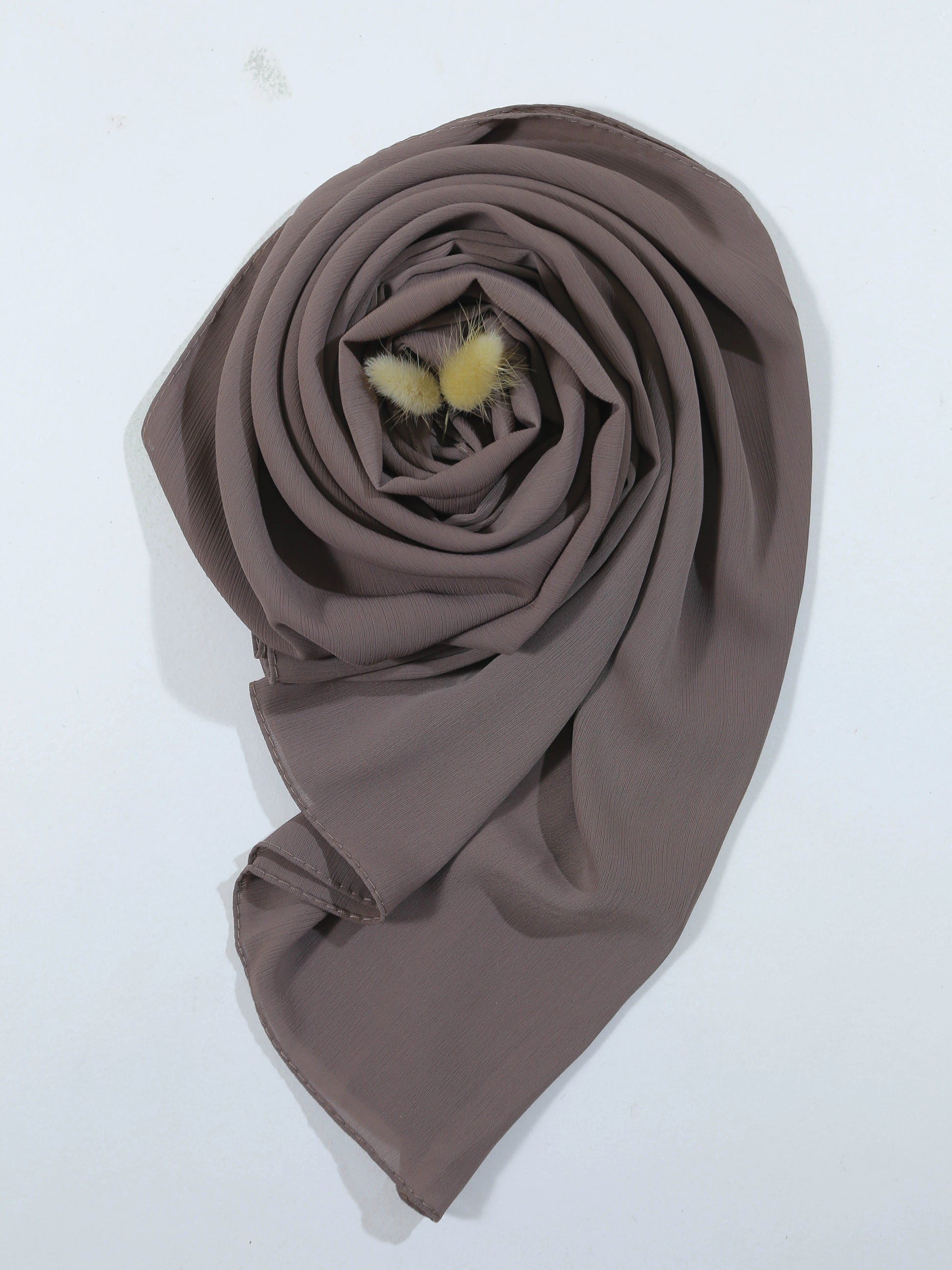 Brown scarf with fluffy pom-poms on a white background