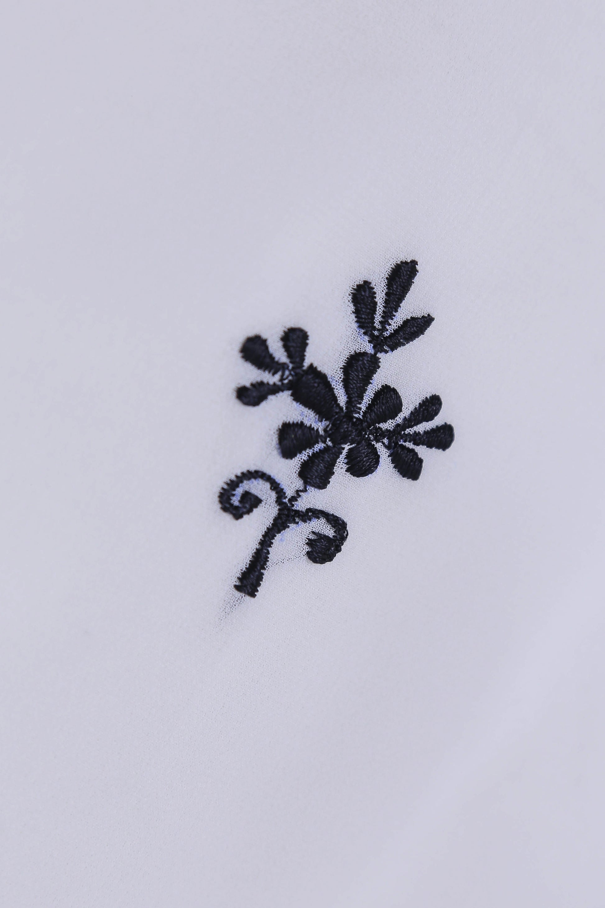 Black floral embroidery on a white fabric background