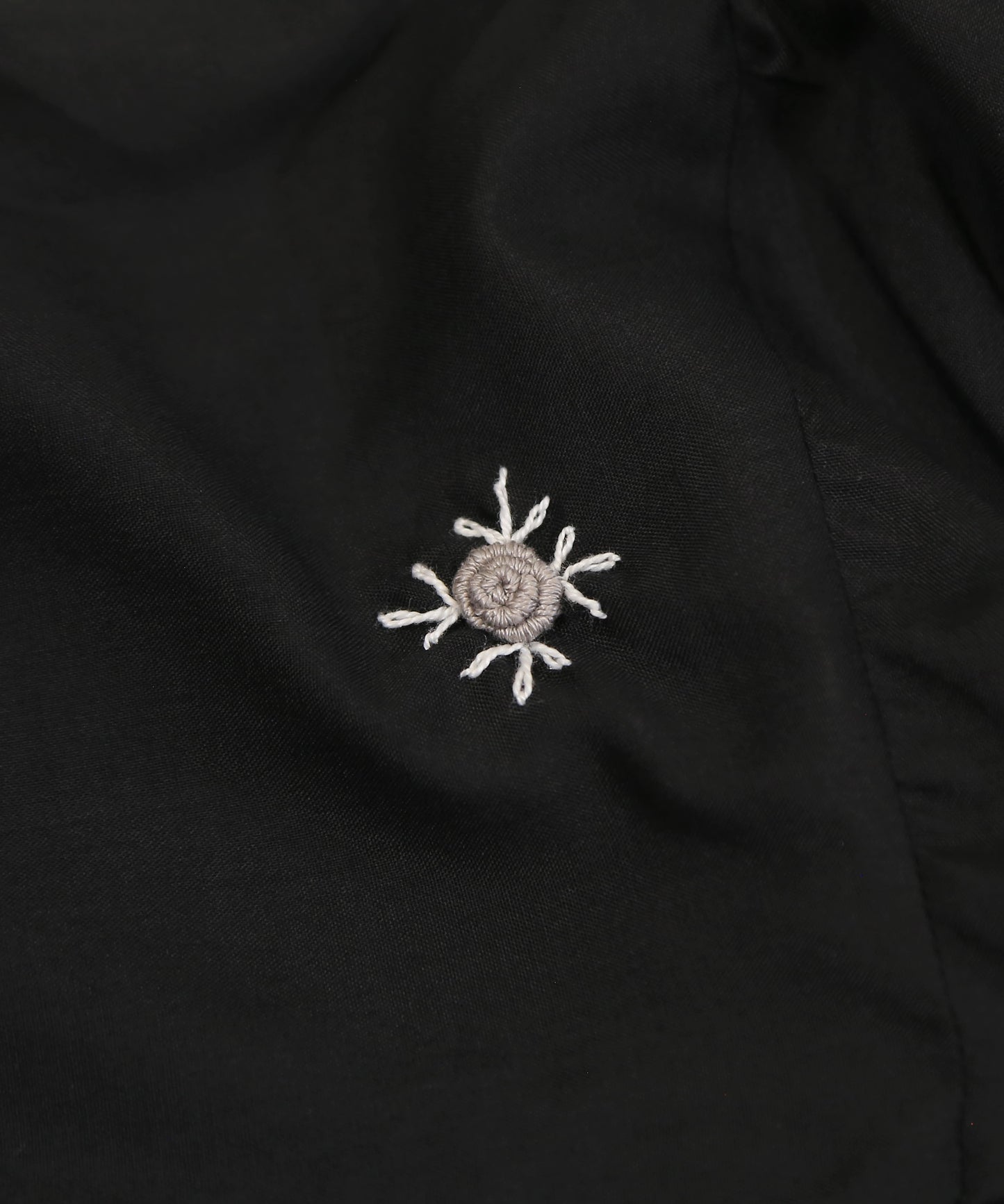 Embroidered sun design on a black fabric background