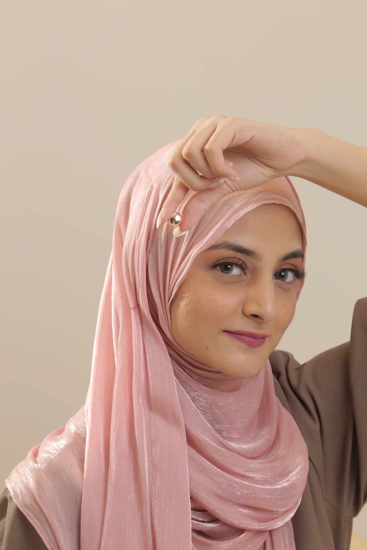 Woman wearing a pink hijab against a plain background