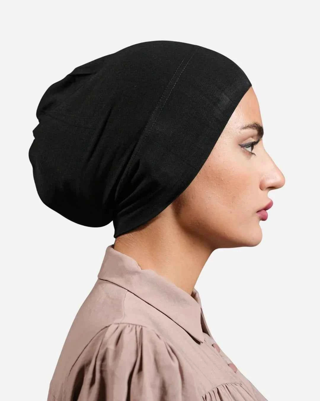 Woman wearing a black headscarf against a plain background
