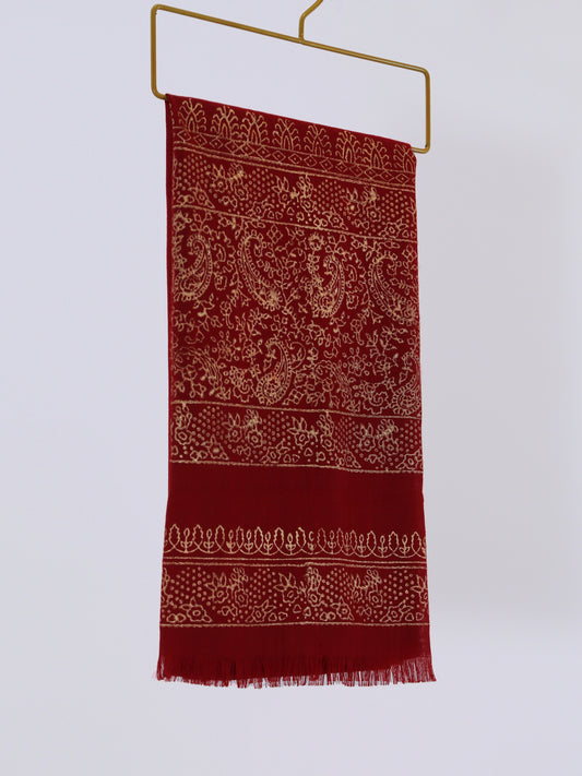 Red scarf with white patterns on a hanger against a white background