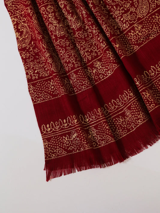 Red scarf with gold patterns on a white background