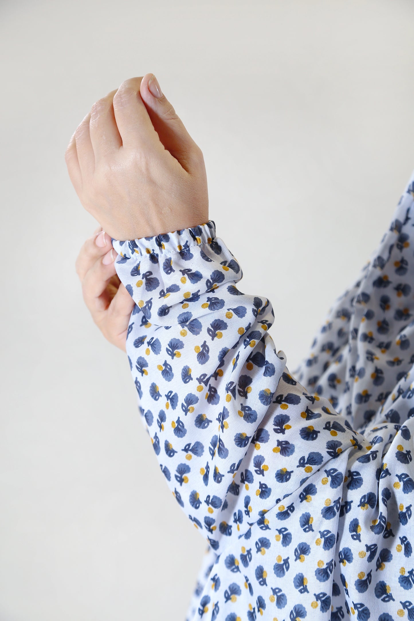 Close-up of a person wearing a floral-patterned shirt with a plain background