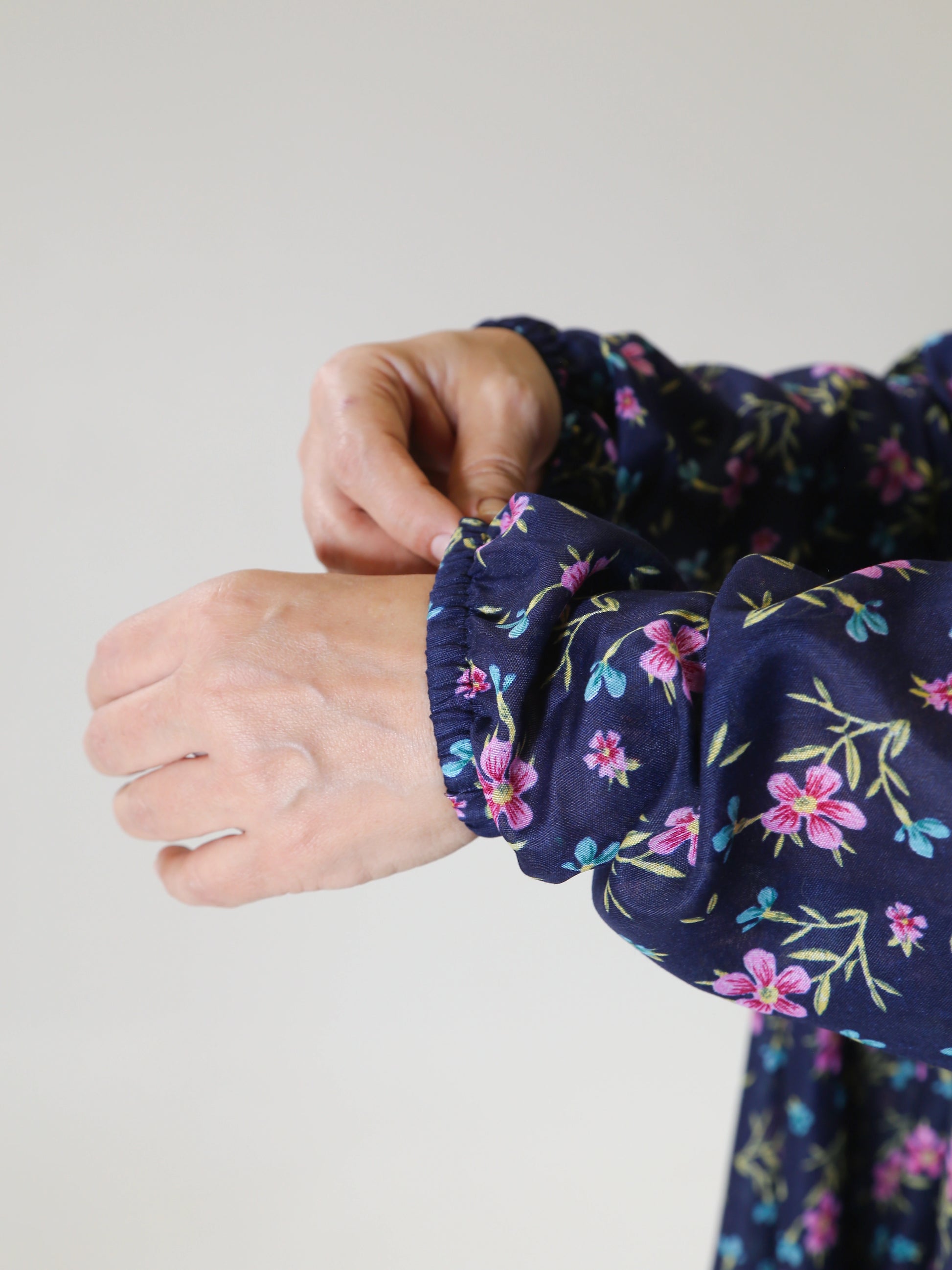 Navy blue floral-patterned scrunchie on a wrist against a light gray background