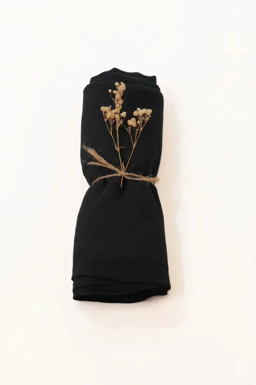 Black fabric with dried flowers tied with twine on a white background