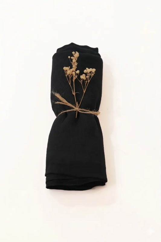 Black fabric with dried flowers tied with twine on a white background