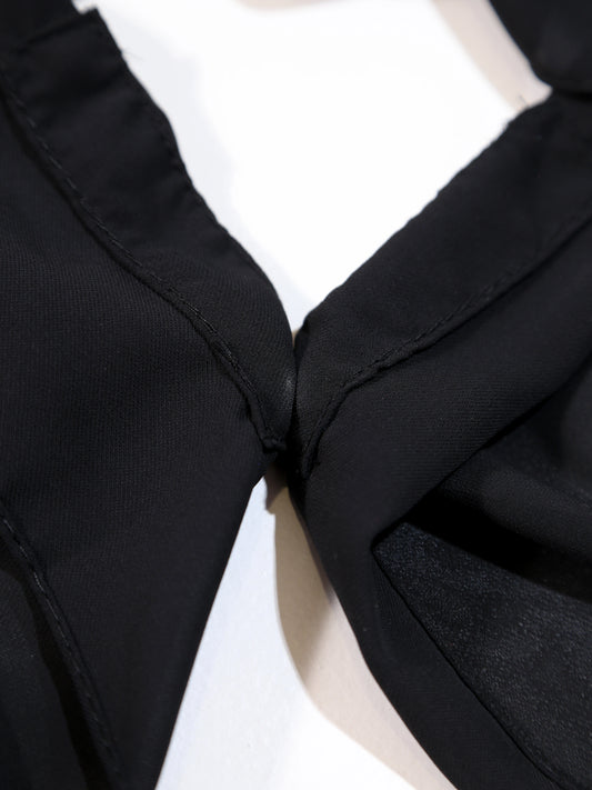 Close-up of a black garment with a bow detail on a white background